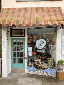 Front of a small cafe with a green door and large window.