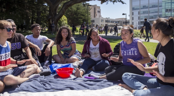 students sitting on a blanket on the quad on a sunny day